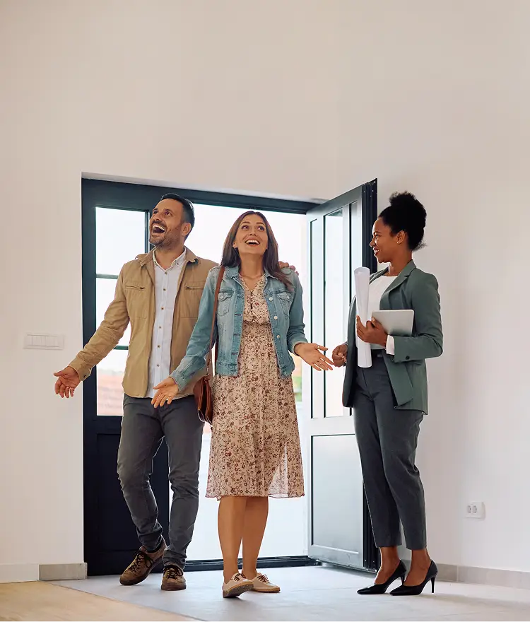 Real estate agent showing a couple around a bright, empty property interior.