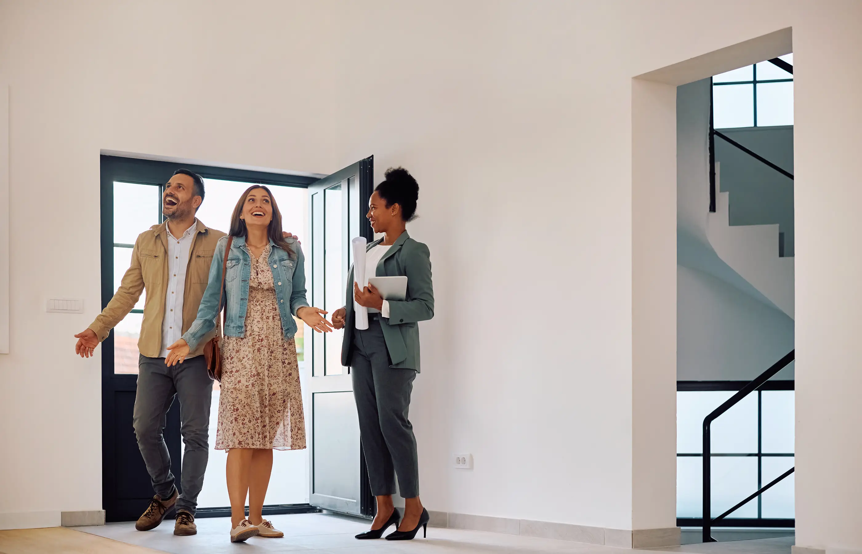 Real estate agent showing a couple around a bright, empty property interior.