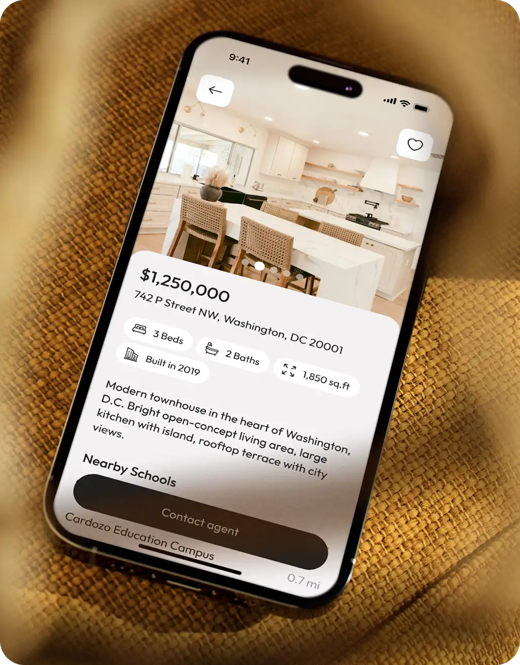 Phone lying on woven fabric showing a property listing page with price, address, beds, baths, size and a Contact agent button.