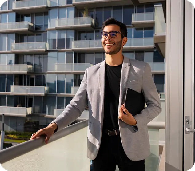 Real estate agent standing on a balcony in front of an apartment building.