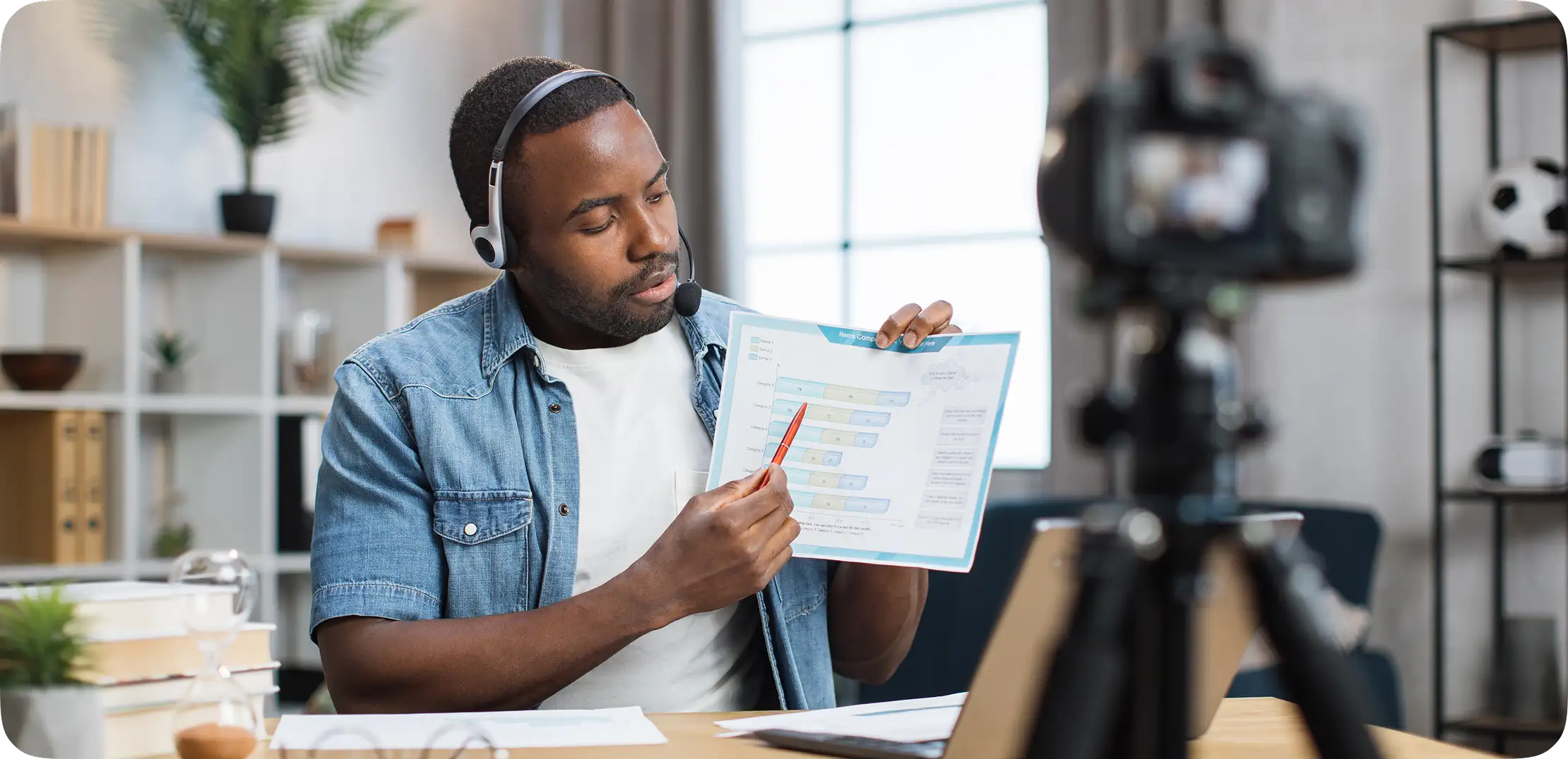 Tutor in a headset showing a chart to the camera while leading an online lesson.