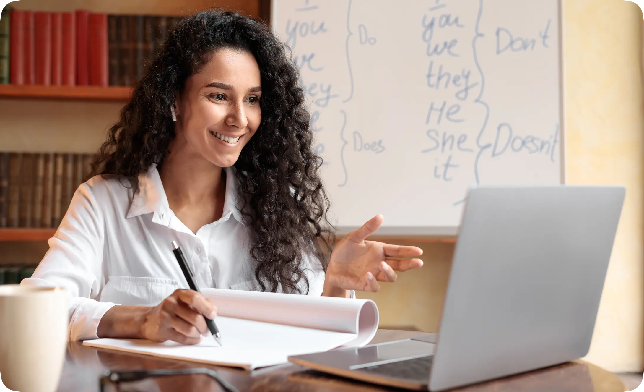 Woman writing notes while studying on a laptop with the learning platform.