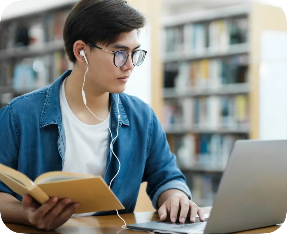 Student wearing headphones reading a book during a remote learning session.
