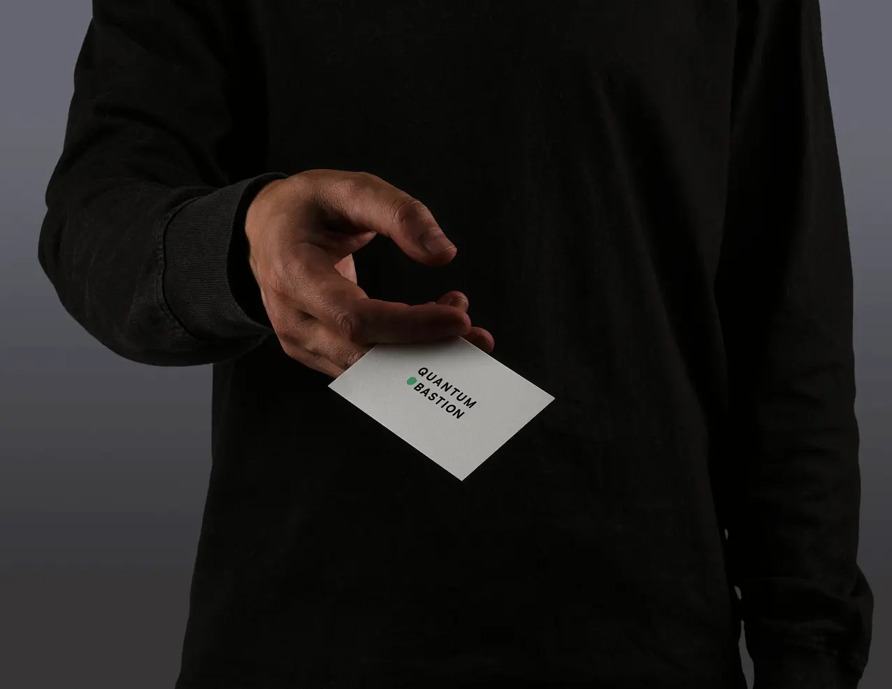 Person in black handing over a business card.