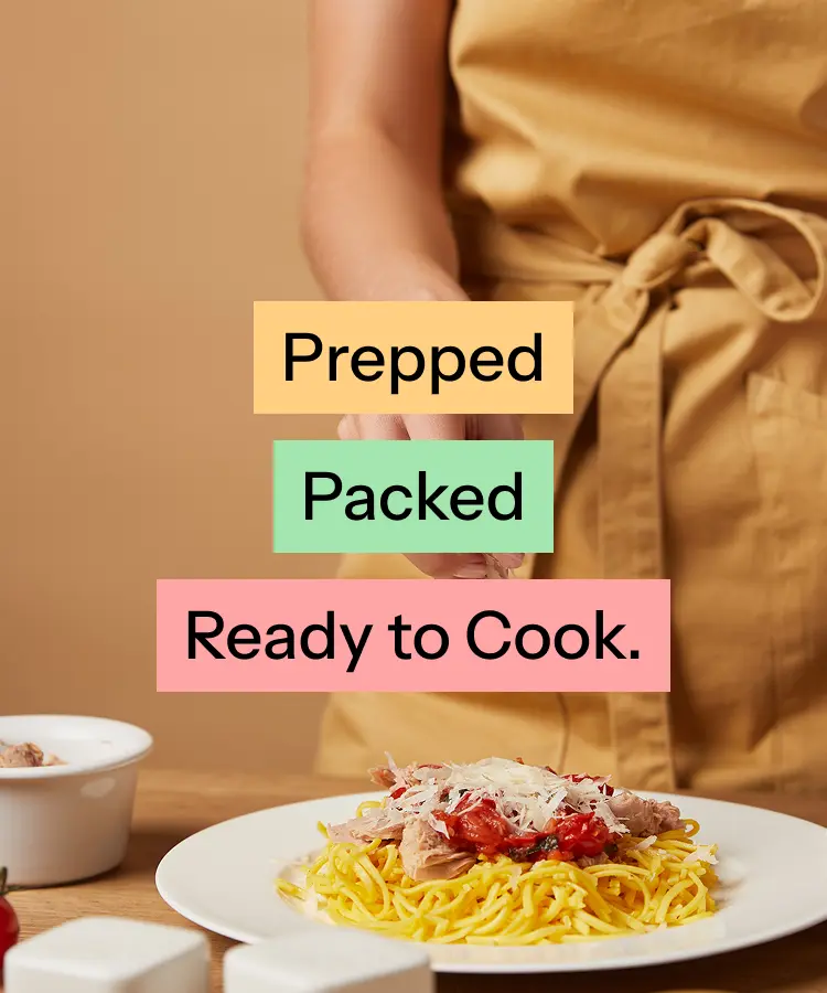 Cook in an apron plating pasta, overlaid with the words Prepped, Packed, Ready to Cook.